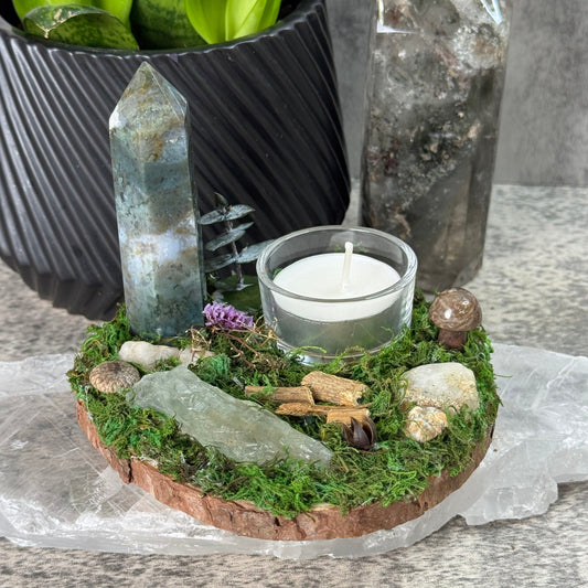 Small garden with a candle, stones, and plants on a stone surface