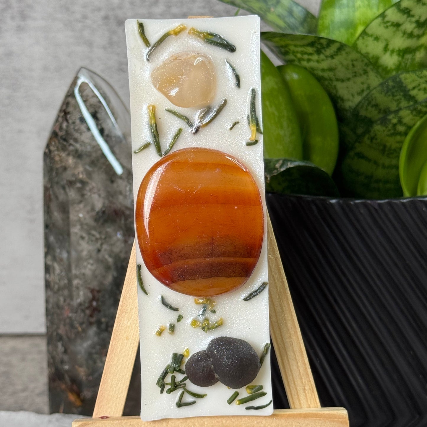 Decorative soap with a wooden stand on a textured surface with greenery in the background