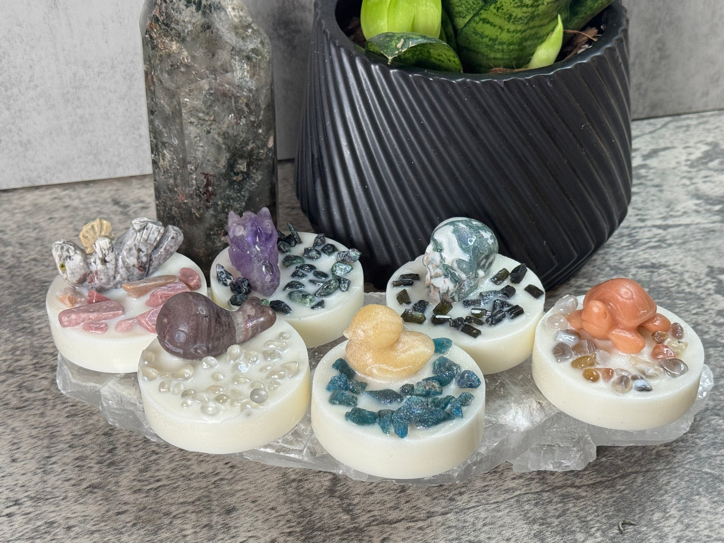 Decorative stones with embedded crystals and small figurines on a stone surface.