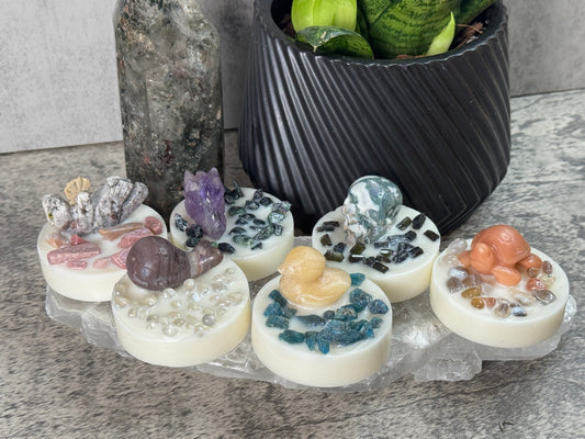 Decorative stones with embedded crystals and small figurines on a stone surface.