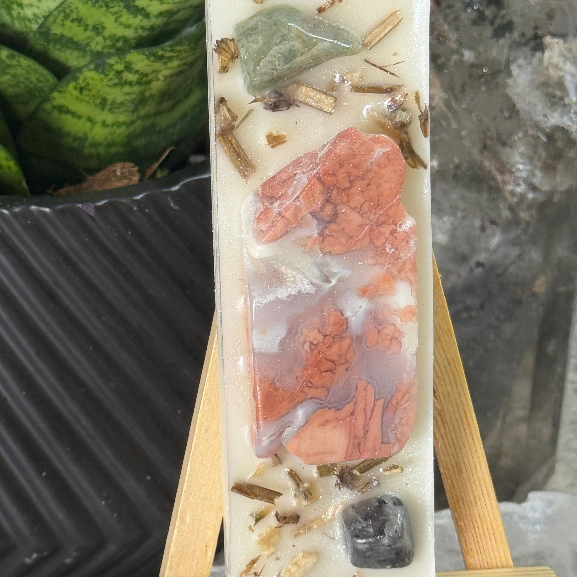 Decorative stone with embedded natural elements on a wooden stand