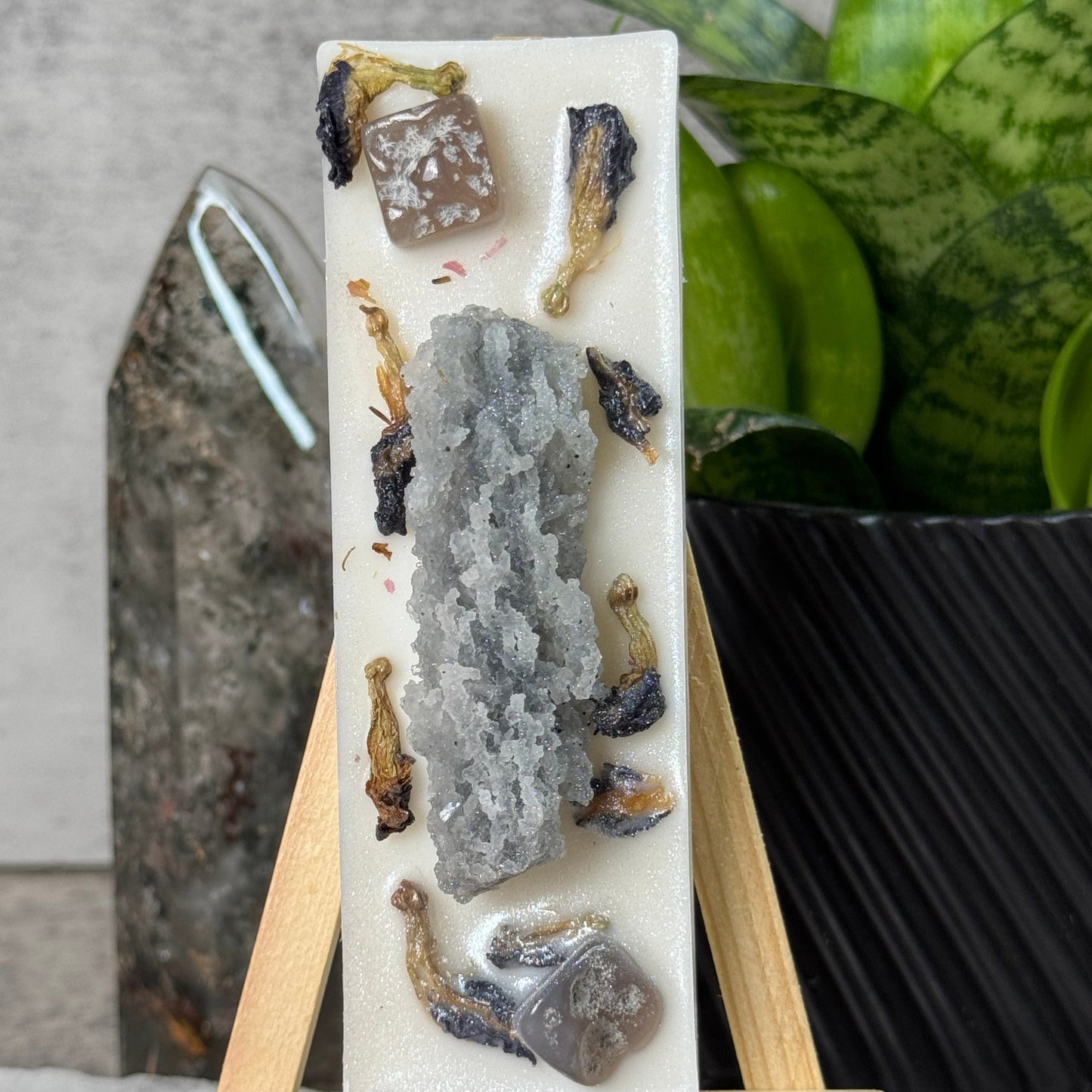 Decorative stone with embedded natural elements on a stand against a neutral background