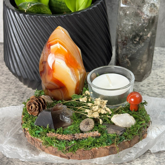 Decorative arrangement with a candle, agate stone, and natural elements on a stone surface