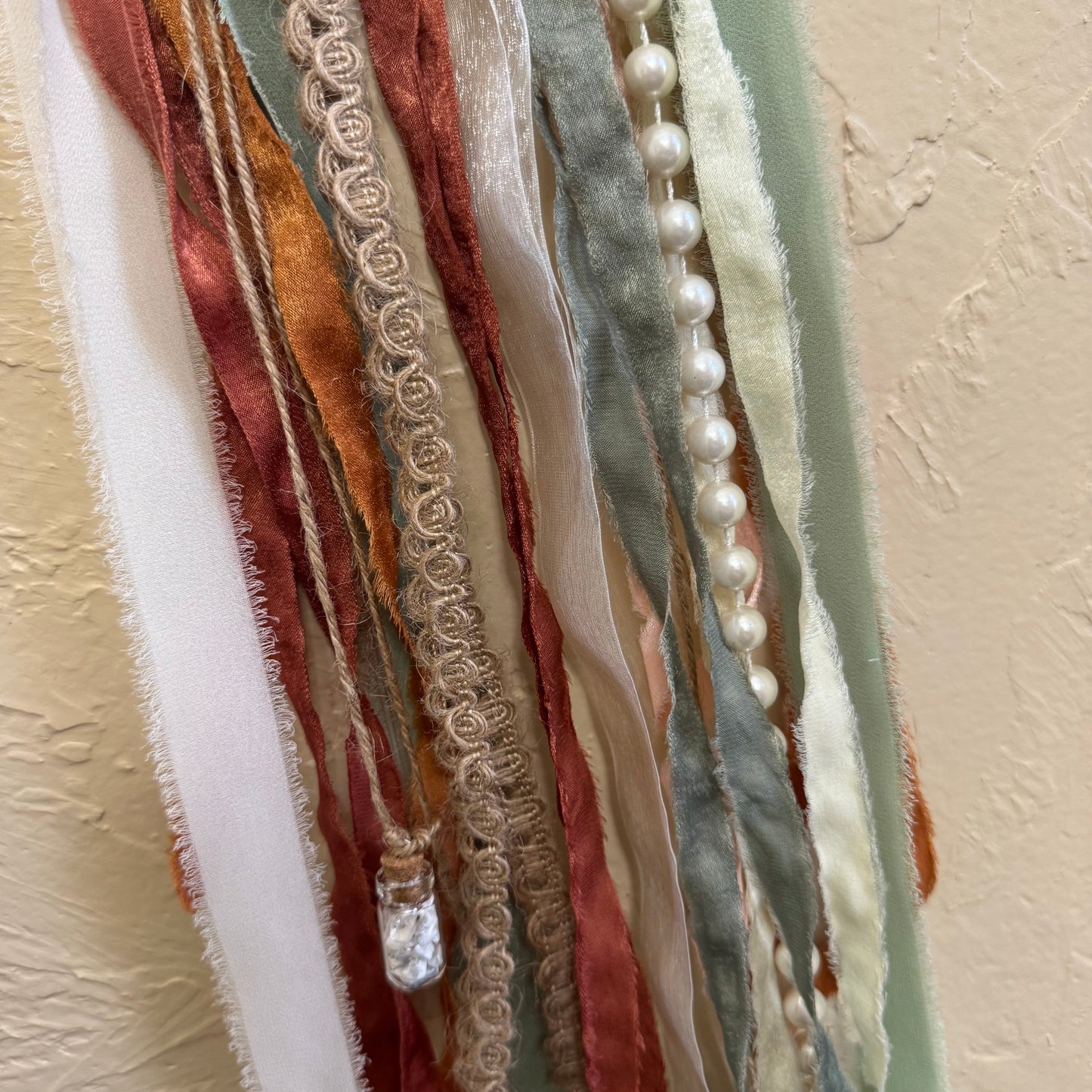 Colorful fabric ribbons with lace and pearls on a beige background
