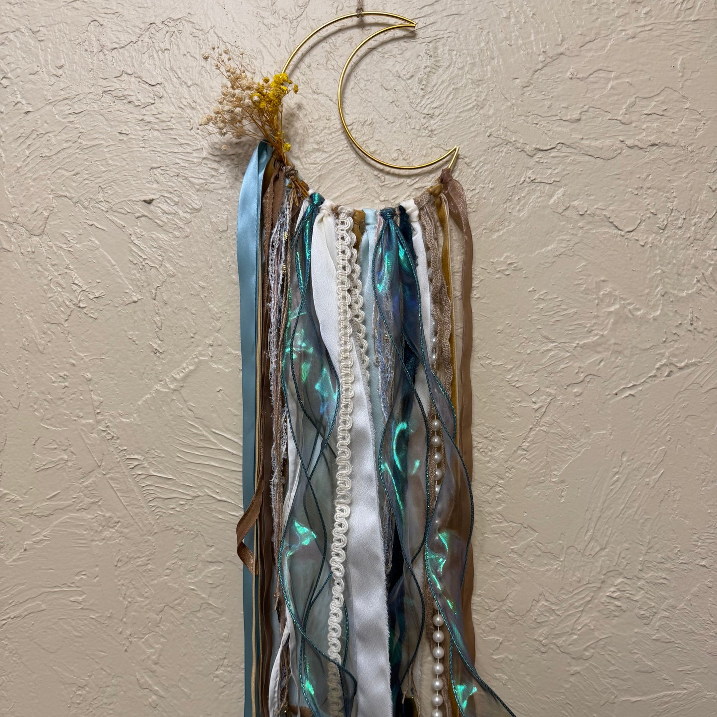 Decorative wall hanging with ribbons on a beige wall